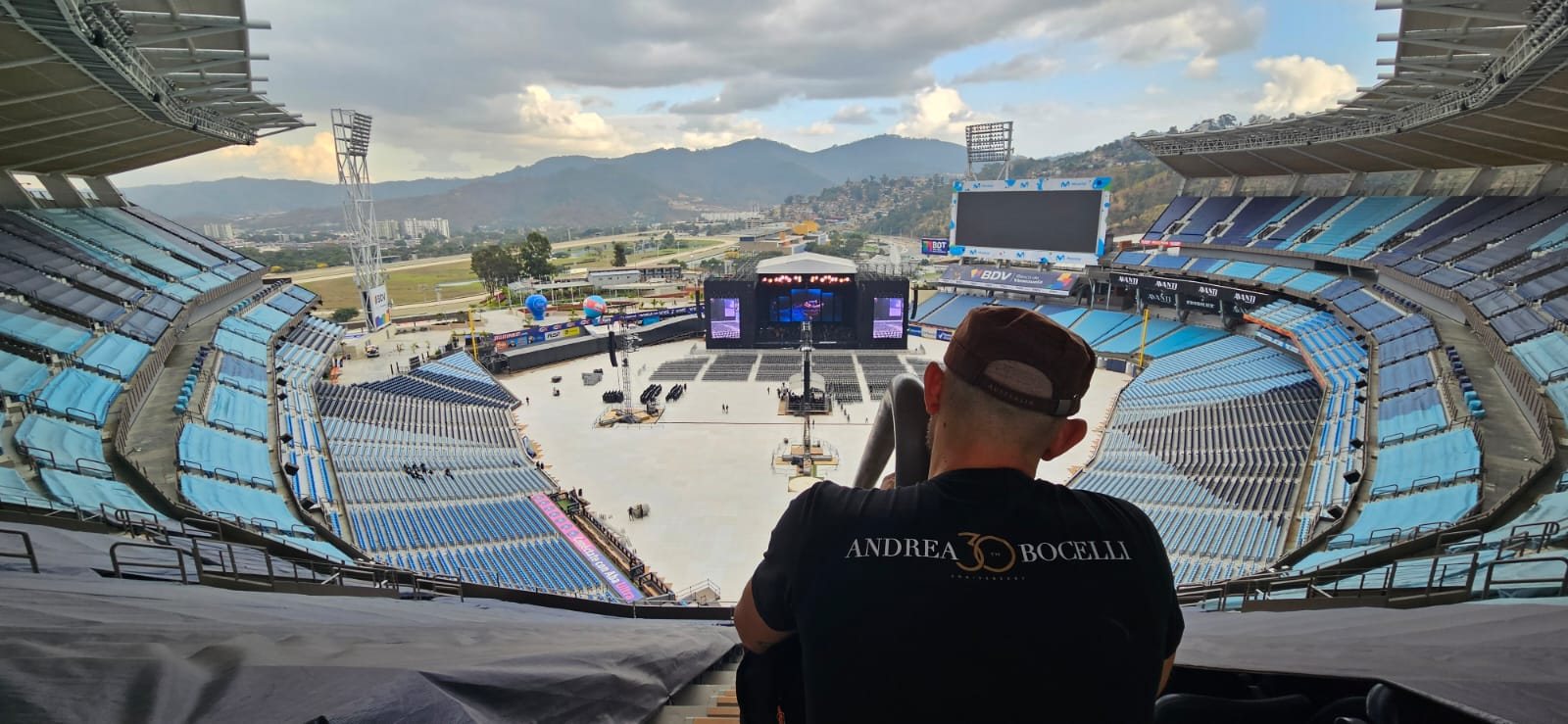 Stadio visto dall'alto durante l'allestimento del concerto, con tecnico in primo piano.