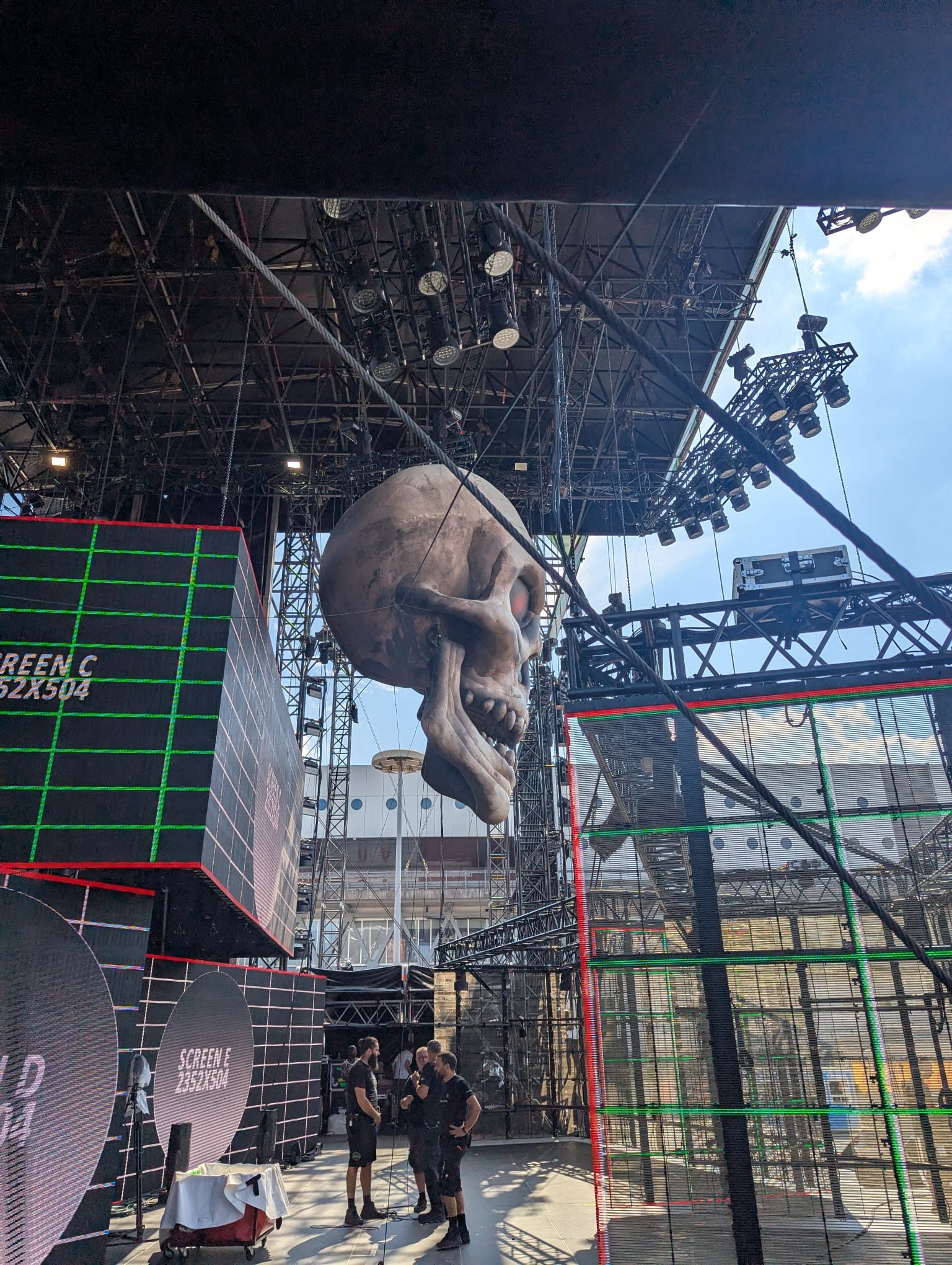 Grande elemento scenografico sospeso sopra il palco, con griglia di rigging e maxischermi.